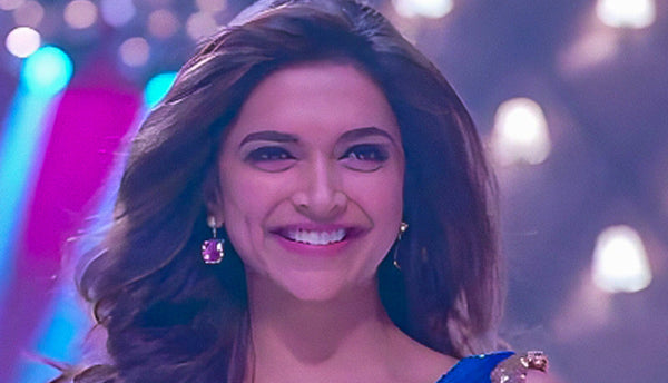 Deepika Padukone in a blue saree with a sparkling blouse against a blurred colorful background