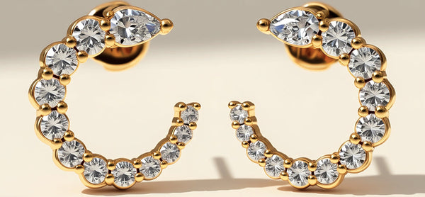 Gold hoop earrings with clear gemstones on a beige background