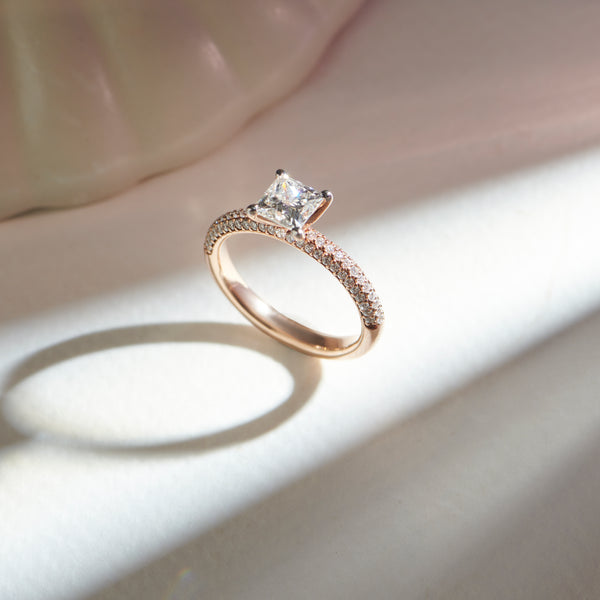 Rose gold ring with a diamond on a light background