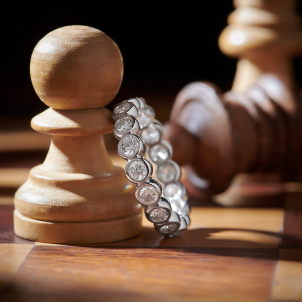 Diamond ring on a wooden chess pawn with a blurred chess piece in the background